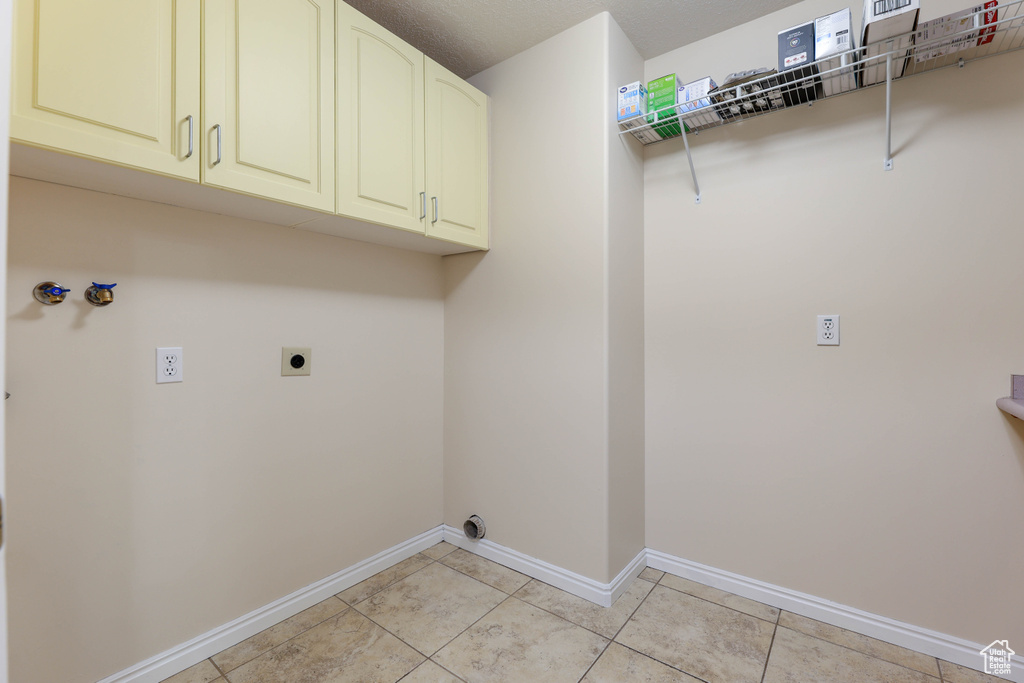 Washroom featuring electric dryer hookup, baseboards, cabinet space, washer hookup, and light tile patterned floors