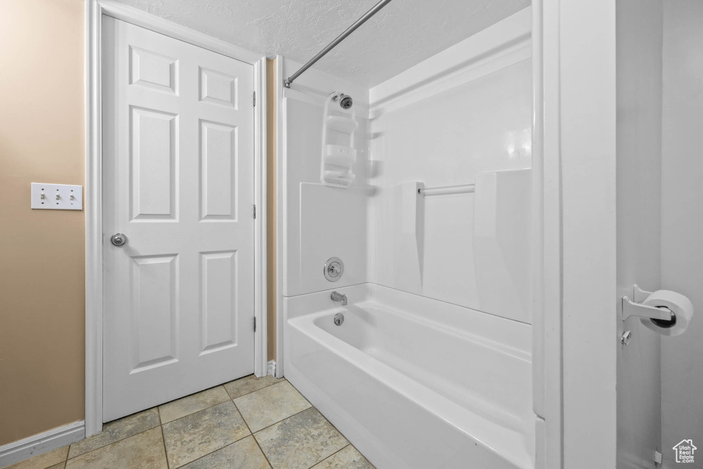 Bathroom with baseboards,  shower combination, and a textured ceiling