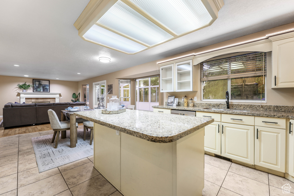 Kitchen featuring a sink, a kitchen island, light tile patterned floors, light stone counters, and recessed lighting