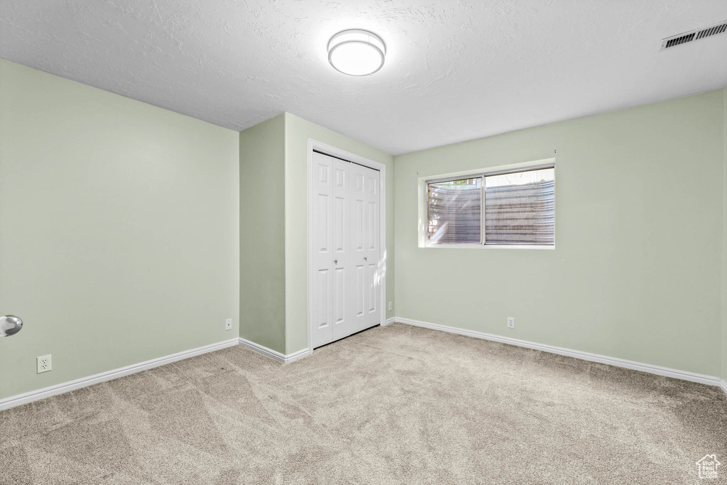 Unfurnished bedroom with carpet flooring, baseboards, a closet, and a textured ceiling