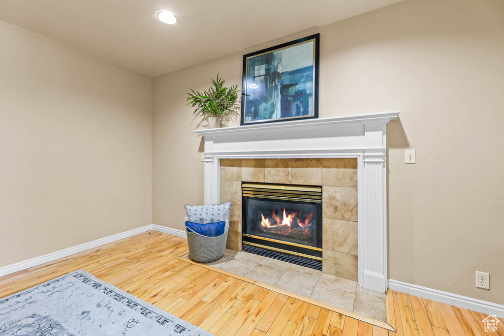 Detailed view of wood finished floors, baseboards, a tiled fireplace, and recessed lighting