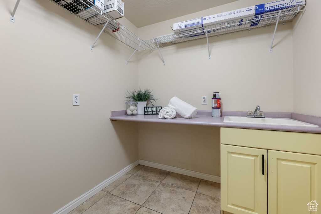 Washroom featuring baseboards, light tile patterned floors, and a sink