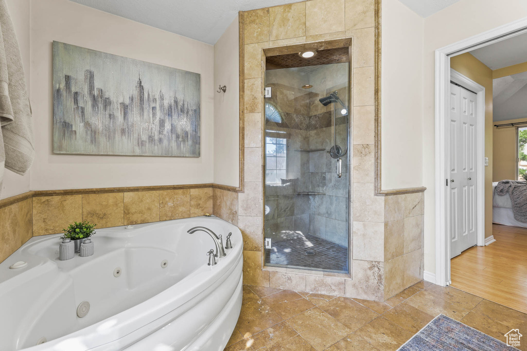 Bathroom with a stall shower, a whirlpool tub, and stone tile flooring