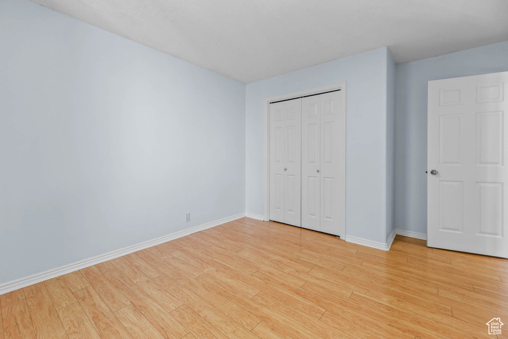 Unfurnished bedroom featuring light wood-style flooring, baseboards, and a closet