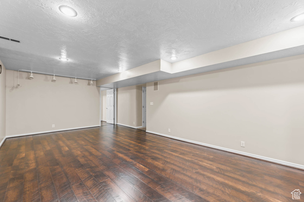 Finished below grade area with a textured ceiling, baseboards, wood finished floors, and recessed lighting