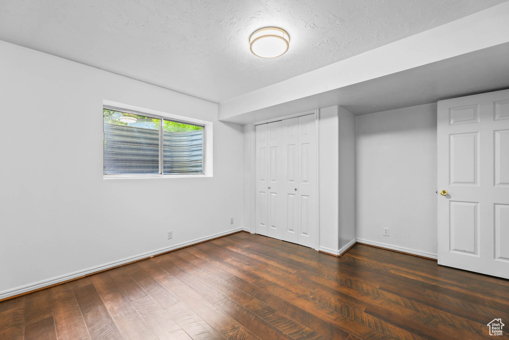 Unfurnished bedroom with baseboards, wood finished floors, a closet, and a textured ceiling