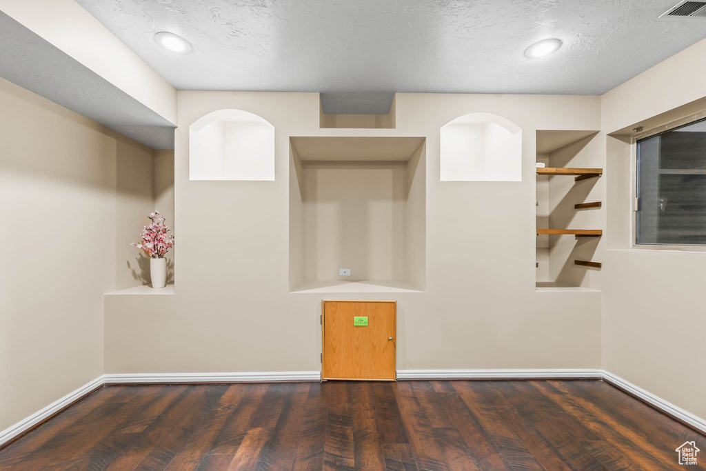 Unfurnished room featuring wood finished floors, a textured ceiling, and baseboards