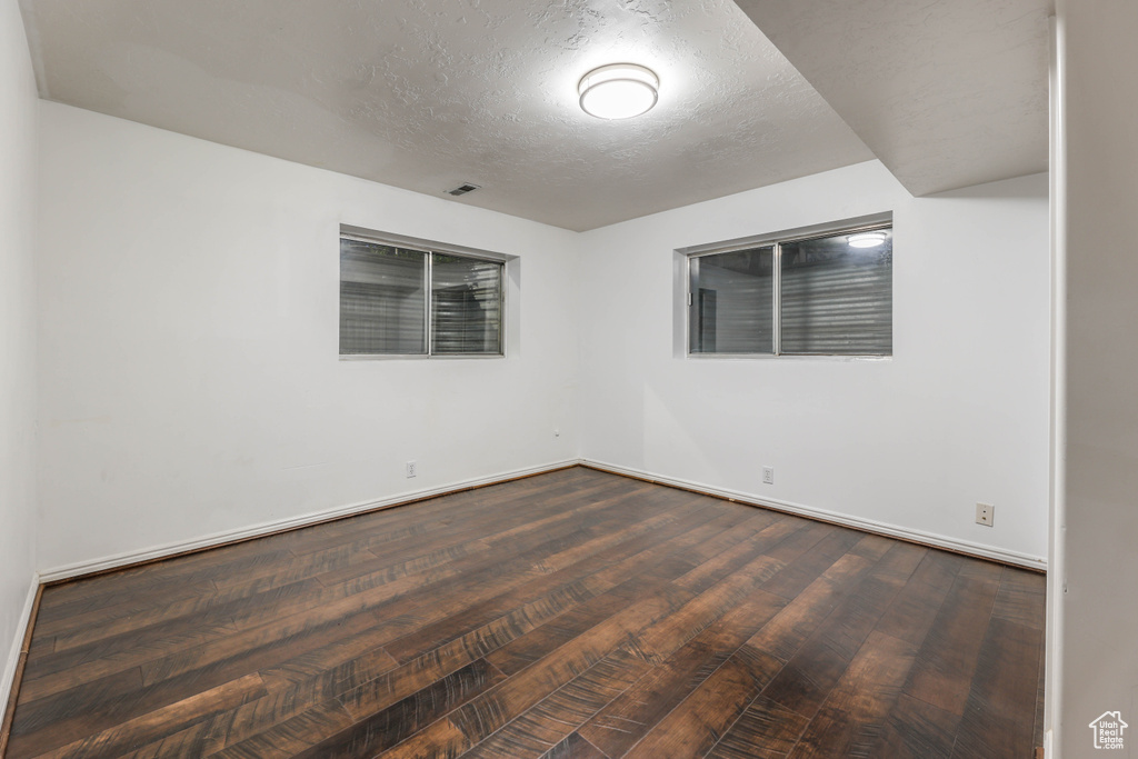 Spare room with baseboards, dark wood-style floors, and a textured ceiling