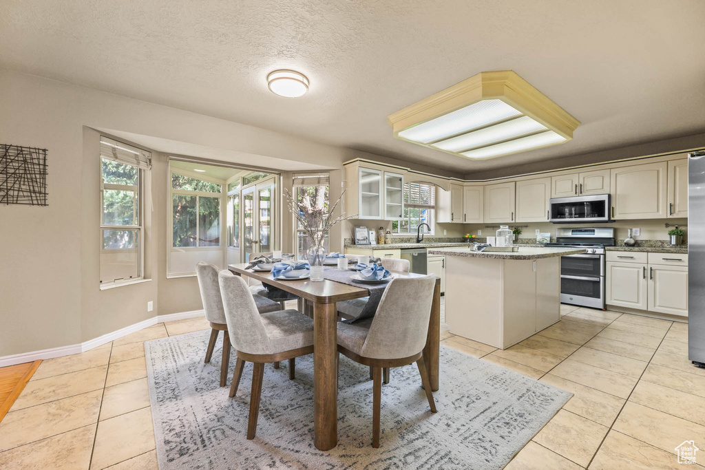 Dining room featuring light tile patterned flooring, baseboards, and a textured ceiling