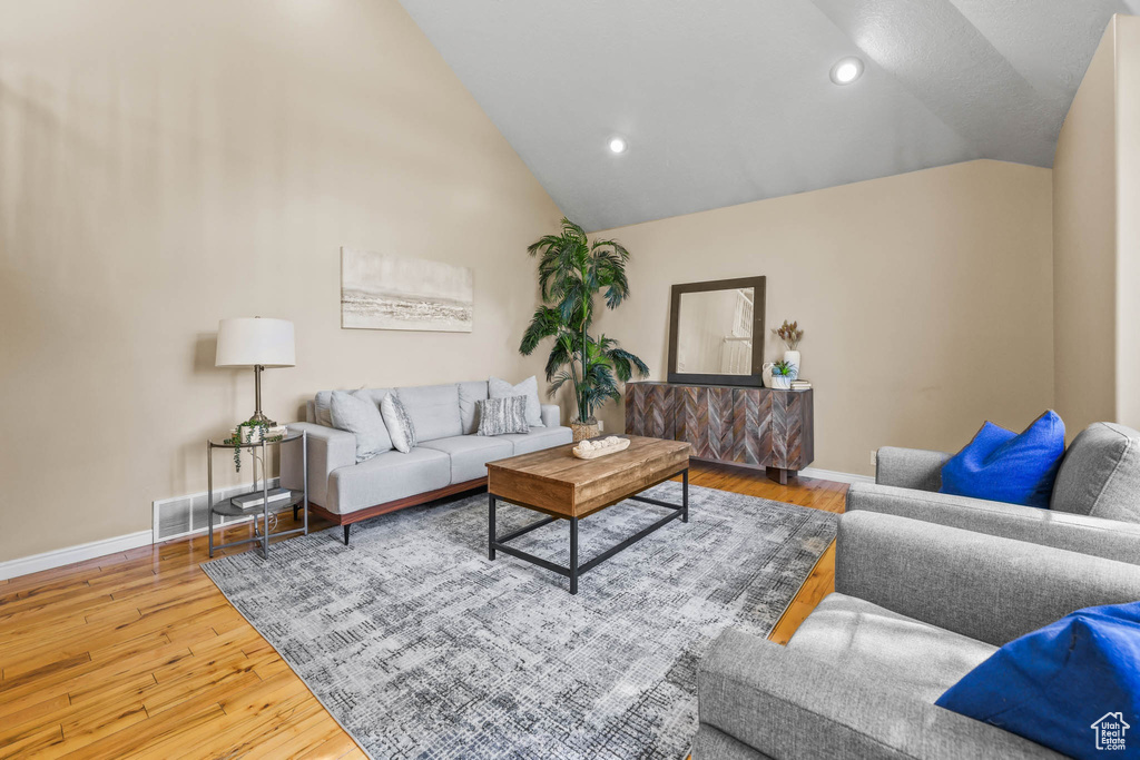Living room with vaulted ceiling, baseboards, wood finished floors, and recessed lighting