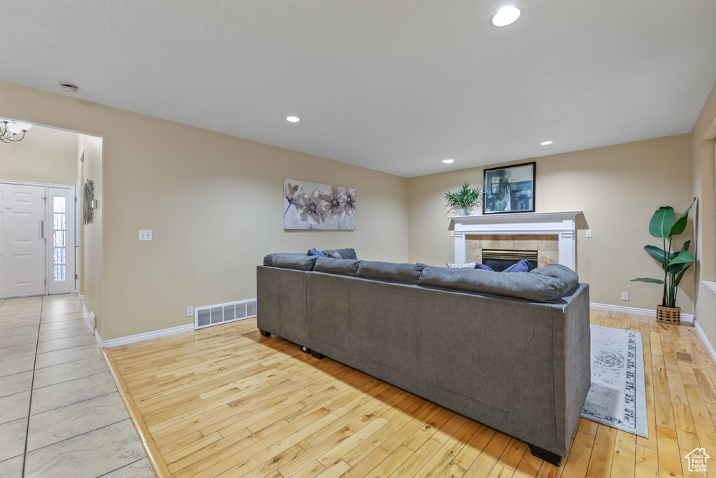 Living room featuring light wood-style floors, a fireplace, baseboards, and recessed lighting