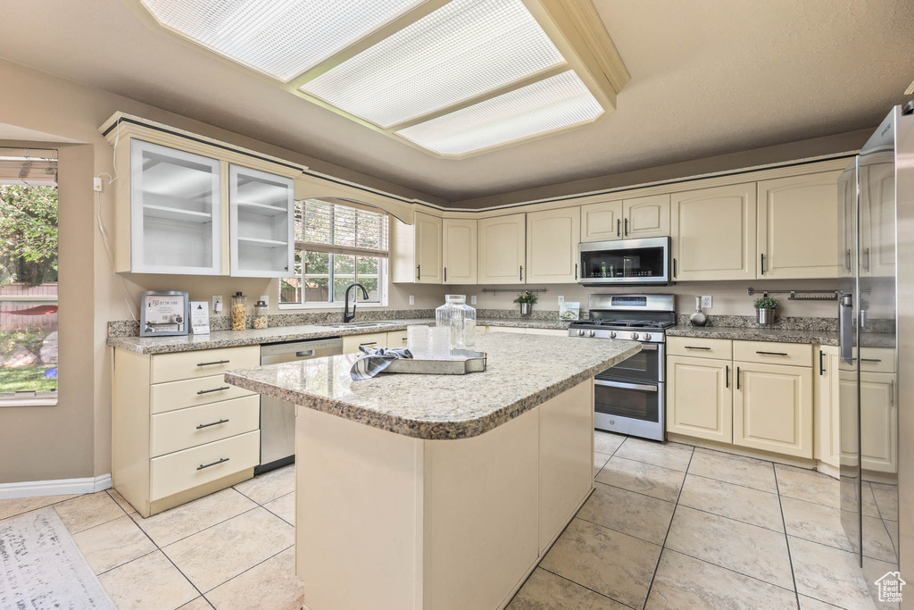 Kitchen featuring appliances with stainless steel finishes, cream cabinets, a center island, and light tile patterned floors