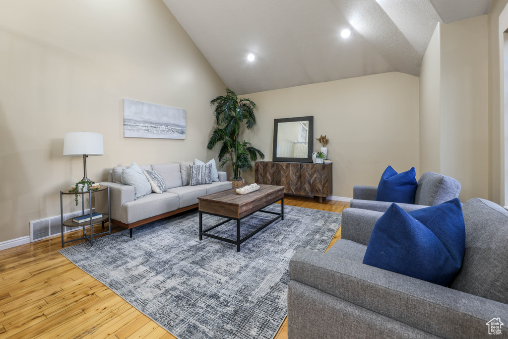 Living room with lofted ceiling, wood finished floors, baseboards, and recessed lighting