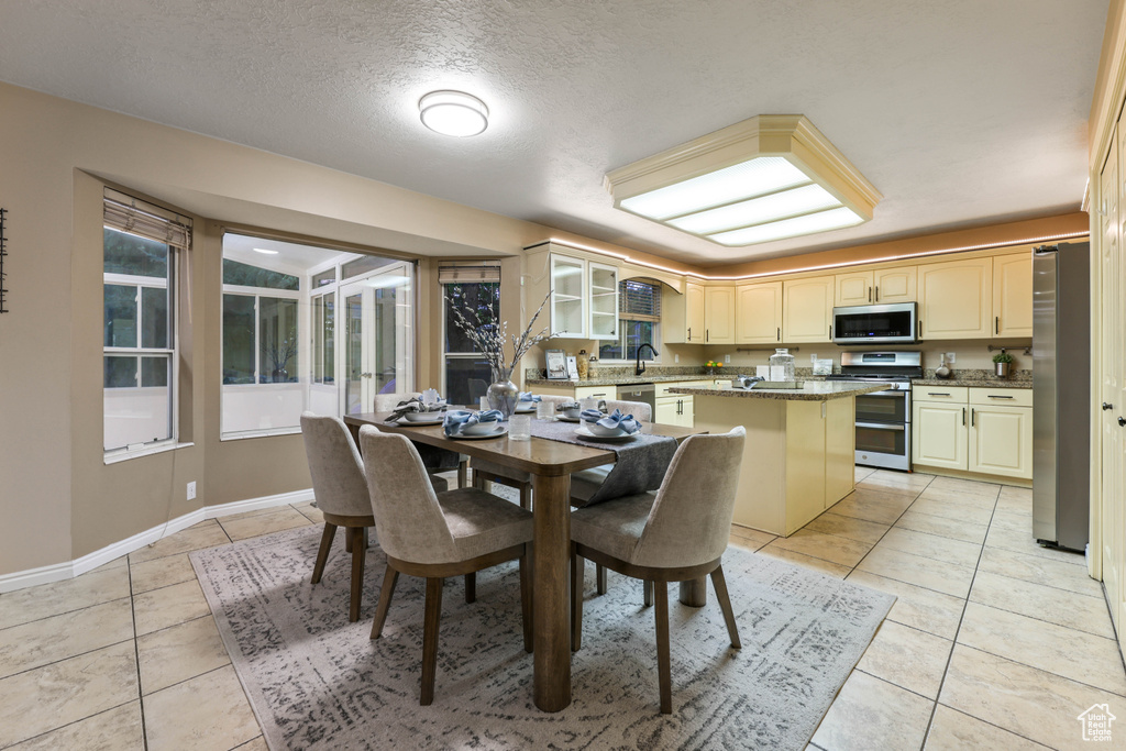 Dining room featuring light tile patterned flooring, a textured ceiling, and baseboards