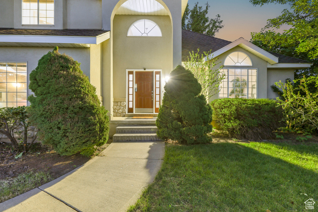 Entrance to property featuring stucco siding and a lawn