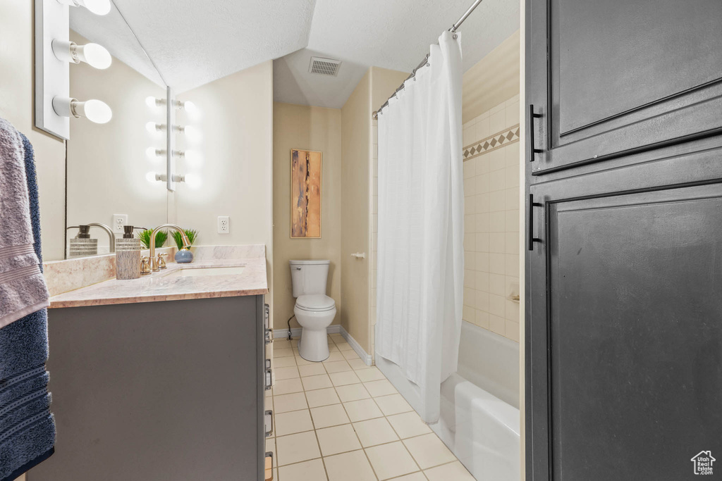 Bathroom with tile patterned floors, vanity, toilet, shower / bath combo with shower curtain, and baseboards