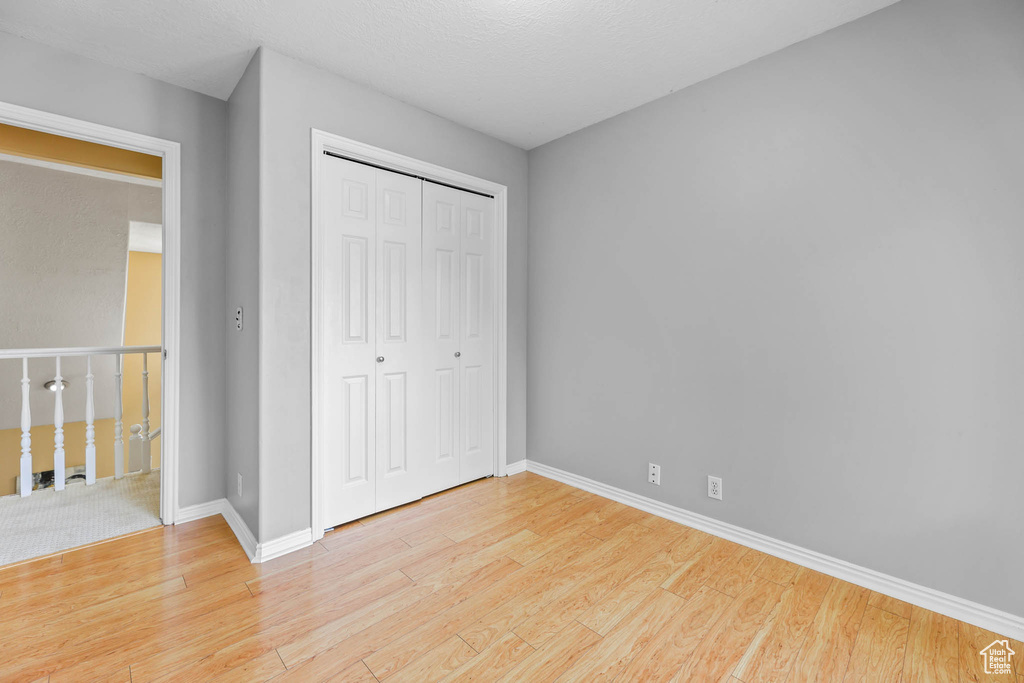 Unfurnished bedroom featuring light wood finished floors, a closet, and baseboards