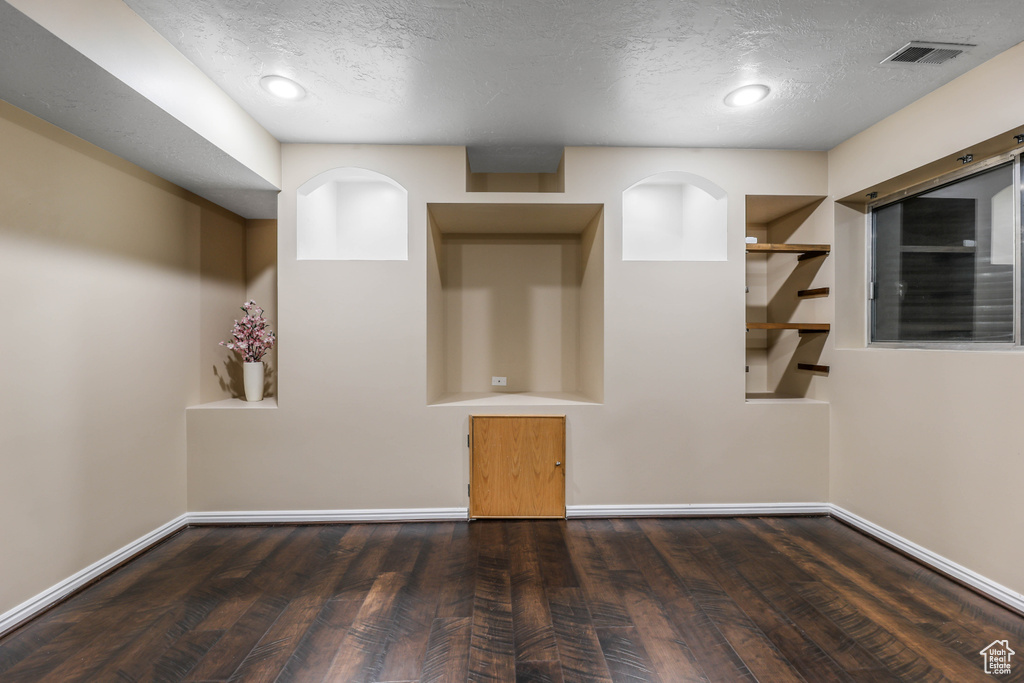 Empty room featuring wood finished floors, a textured ceiling, and baseboards