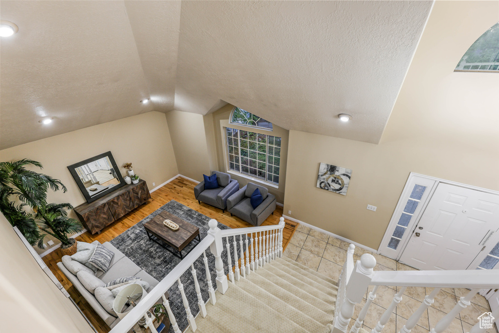 Living room with vaulted ceiling, a textured ceiling, and baseboards