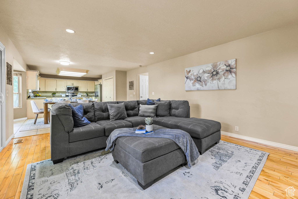 Living area featuring light wood-style floors, baseboards, and recessed lighting