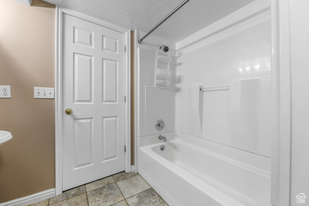 Bathroom with baseboards, a textured ceiling, and tub / shower combination