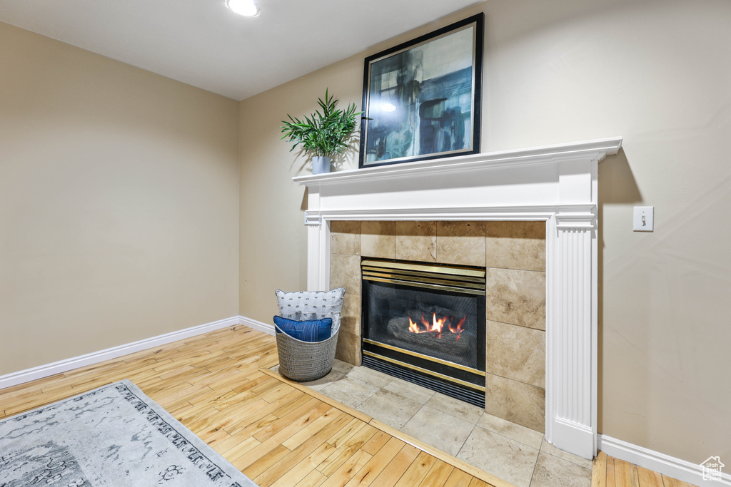 Detailed view of a tiled fireplace, wood finished floors, and baseboards