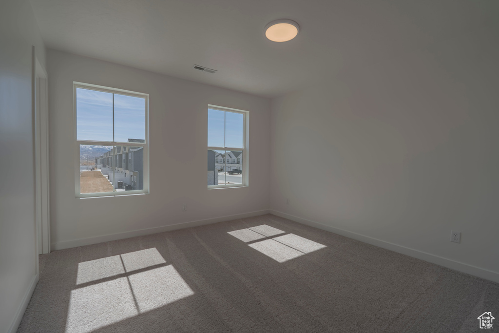 Spare room featuring carpet flooring and baseboards