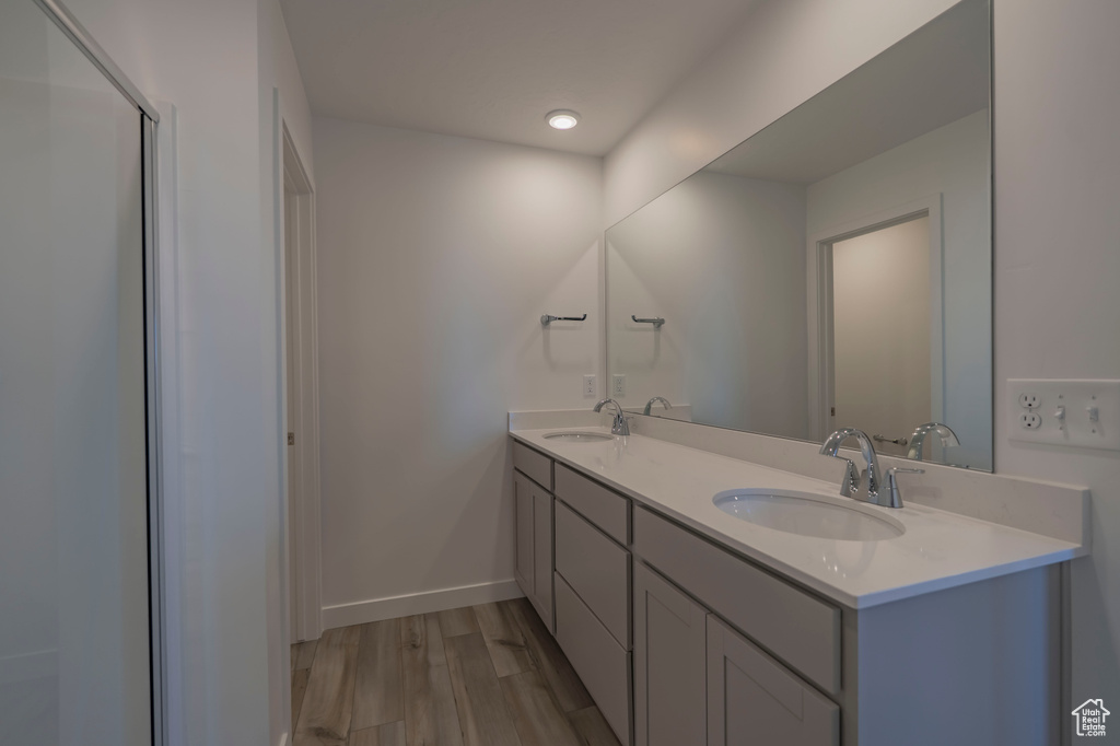 Full bath featuring wood finished floors, double vanity, and baseboards
