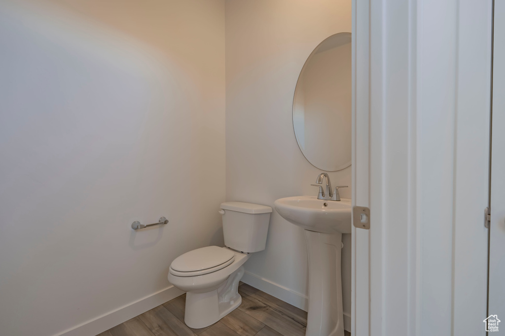 Bathroom featuring baseboards, toilet, wood finished floors, and a sink