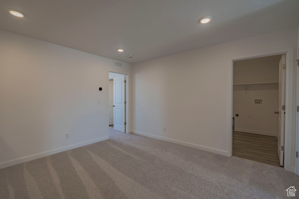 Unfurnished bedroom featuring carpet flooring, baseboards, recessed lighting, and a walk in closet