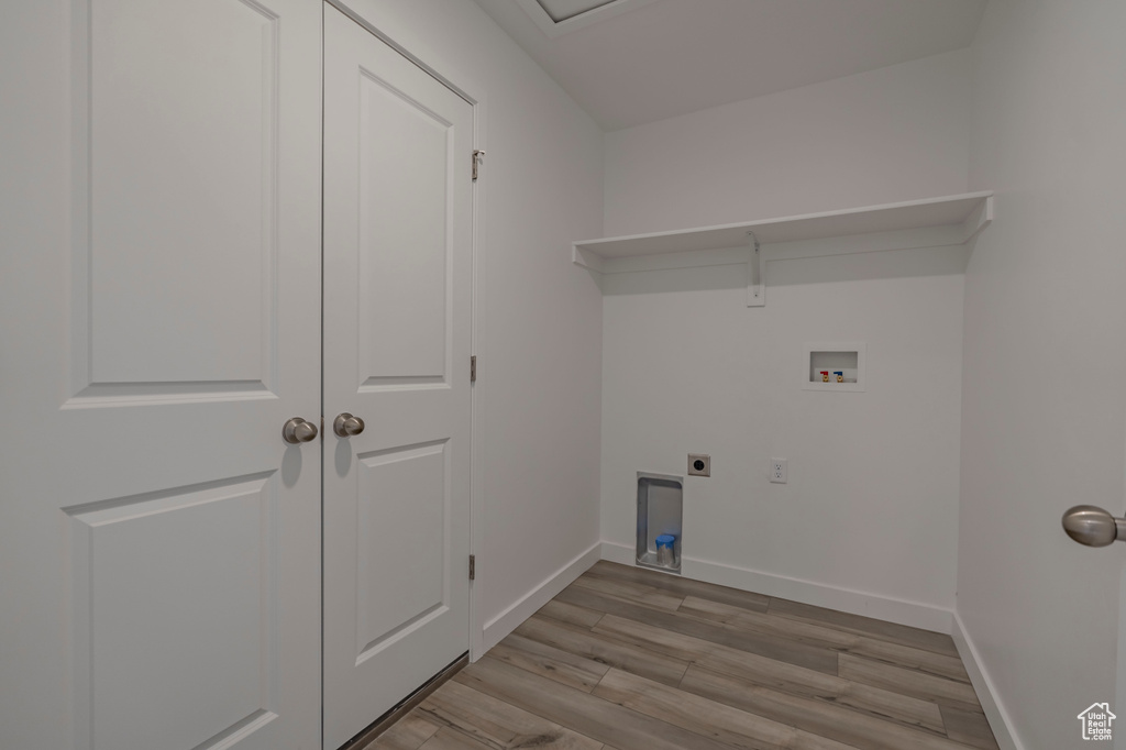 Washroom featuring hookup for an electric dryer, washer hookup, light wood-style flooring, and baseboards