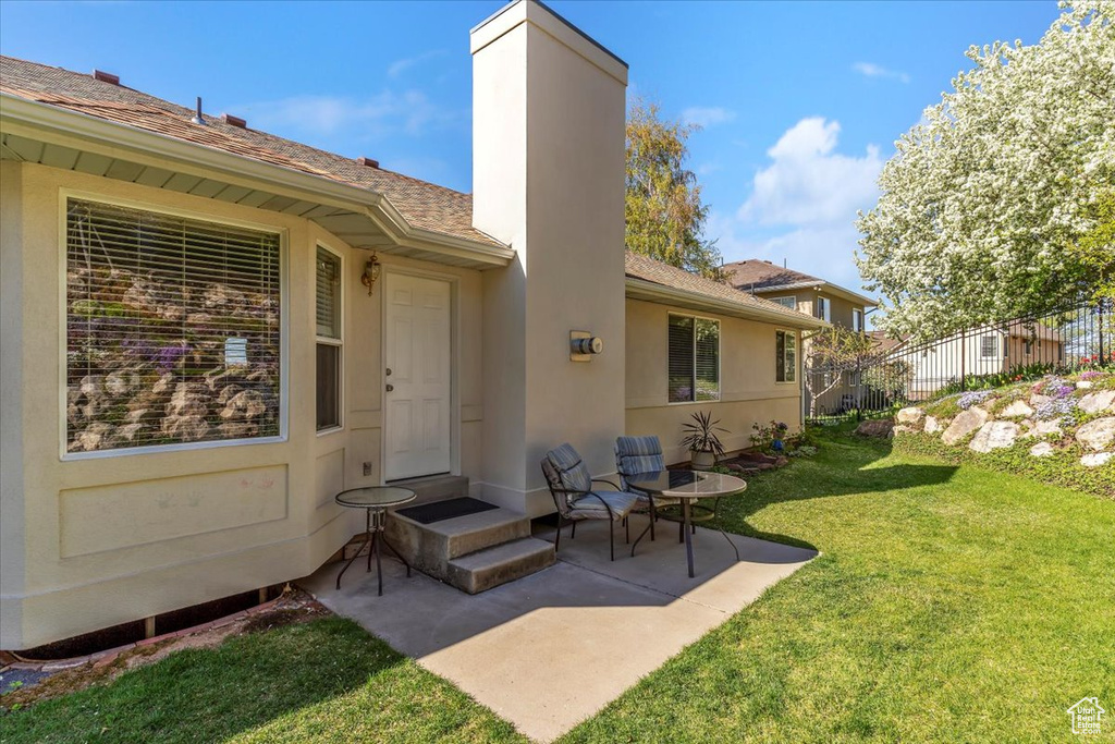 Back of house with stucco siding, a patio, a chimney, and a shingled roof
