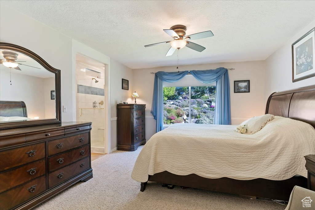 Bedroom featuring light carpet, ensuite bathroom, ceiling fan, and a textured ceiling