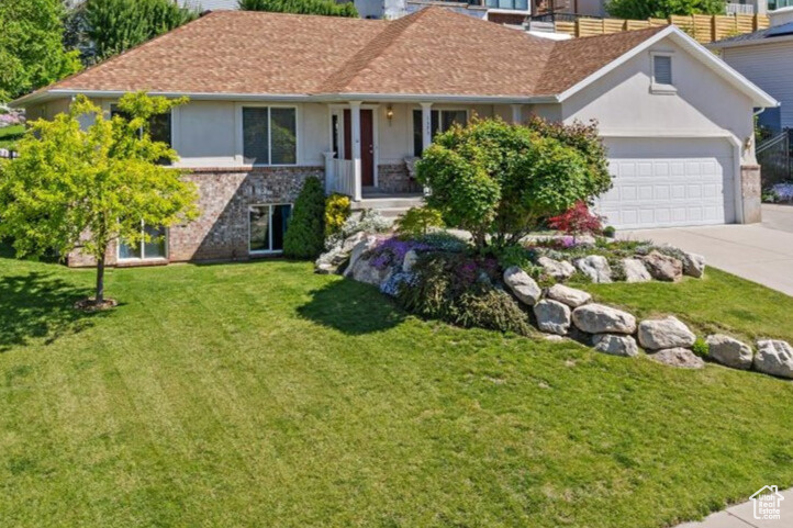 Ranch-style house with a garage, driveway, a front yard, stucco siding, and brick siding
