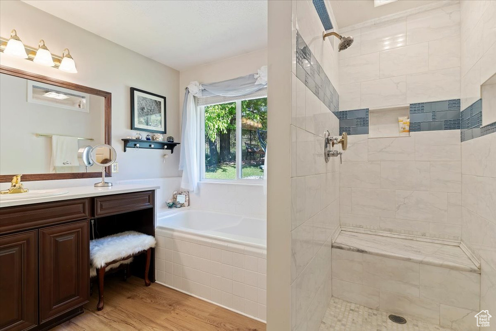 Bathroom with a tile shower, wood finished floors, a bath, and vanity