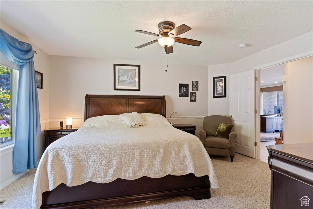 Bedroom with light colored carpet, multiple windows, and a ceiling fan