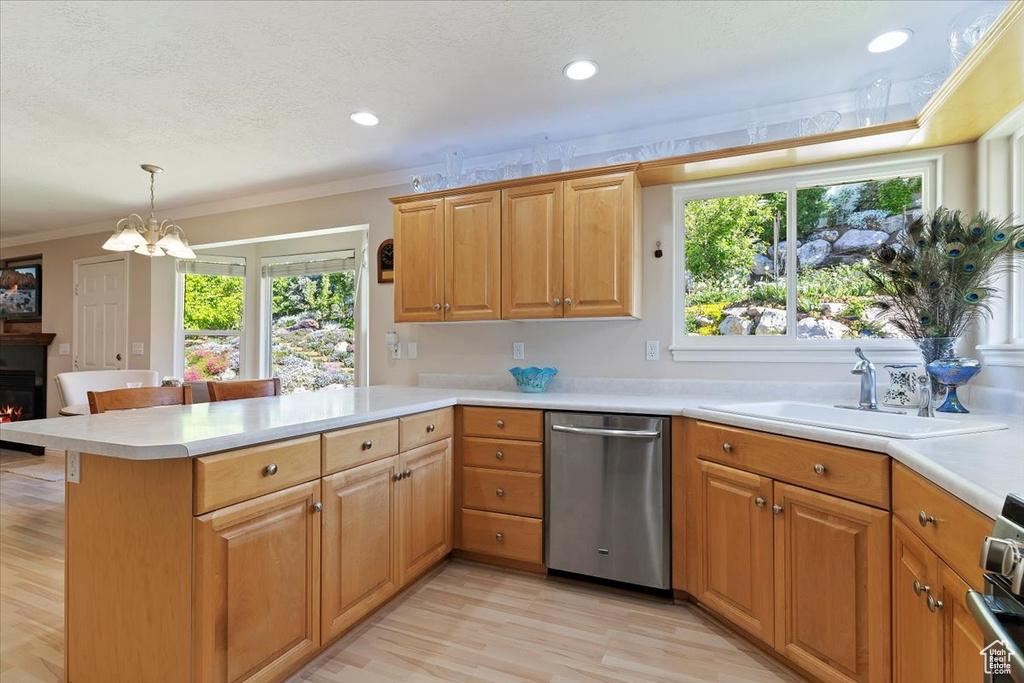 Kitchen featuring dishwasher, light countertops, a peninsula, healthy amount of natural light, and ornamental molding