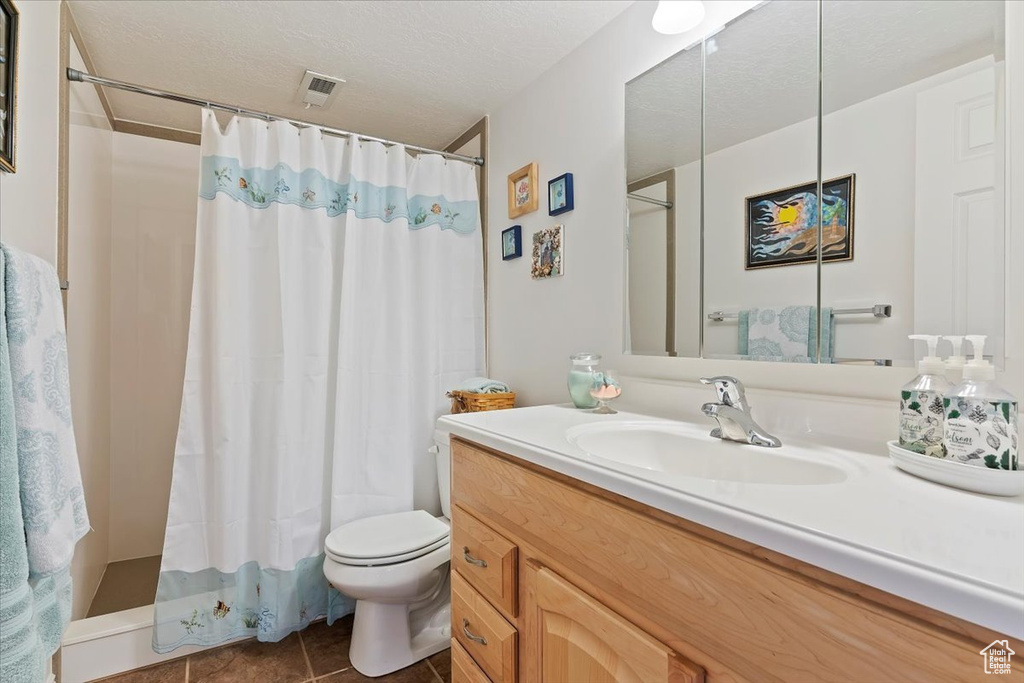 Full bath with toilet, tile patterned floors, vanity, a shower with shower curtain, and a textured ceiling