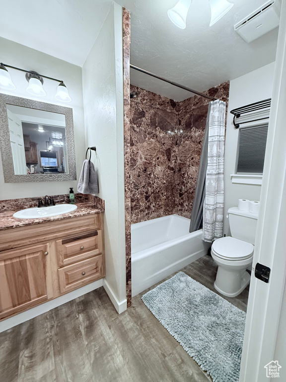 Bathroom featuring wood finished floors, toilet, shower / bathtub combination with curtain, and vanity