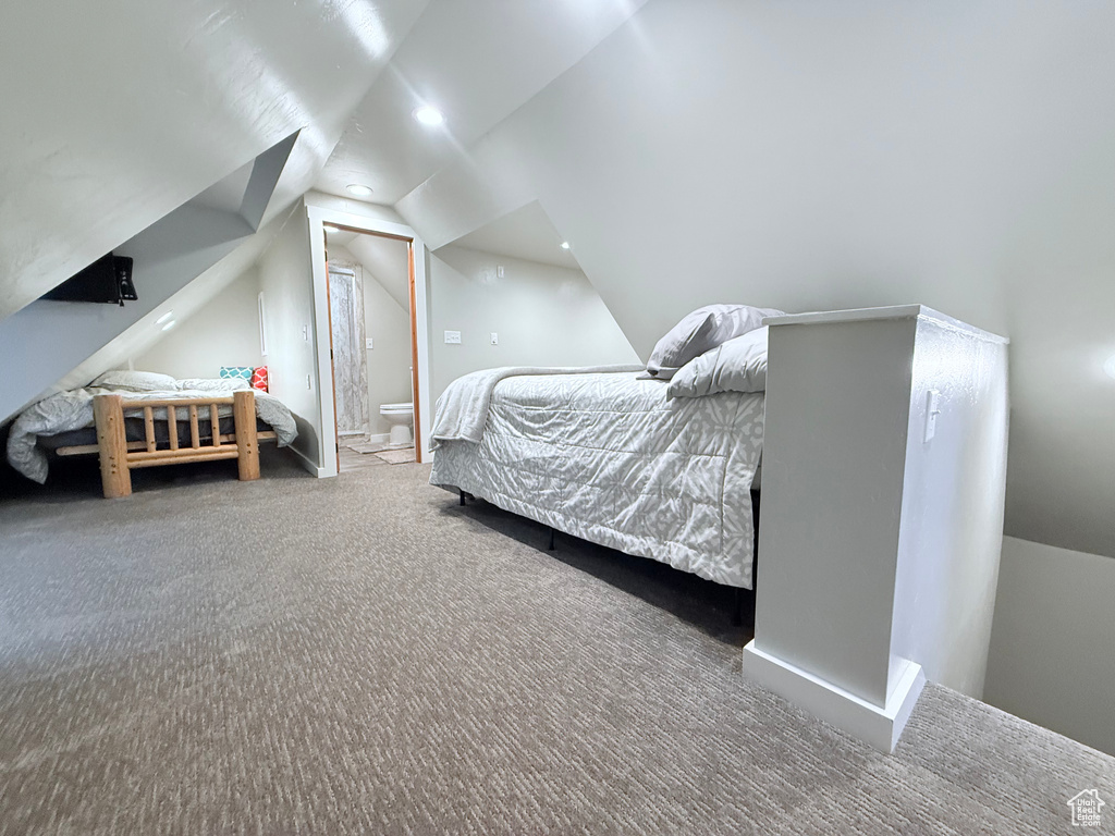 Carpeted bedroom featuring vaulted ceiling and ensuite bath