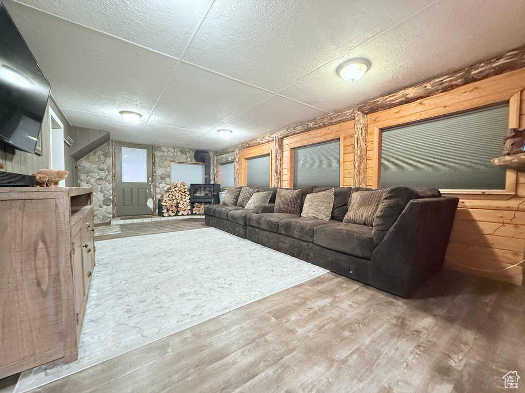 Living room featuring a wood stove, wood finished floors, and a textured ceiling
