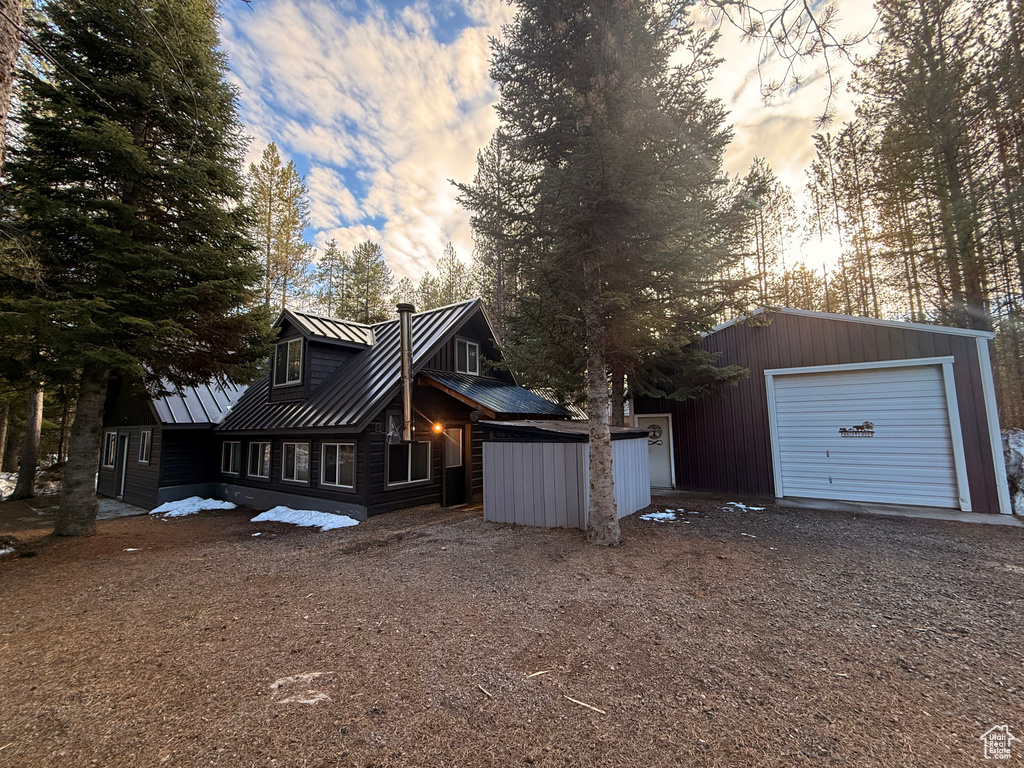 View of side of property featuring dirt driveway, an outbuilding, a standing seam roof, and metal roof