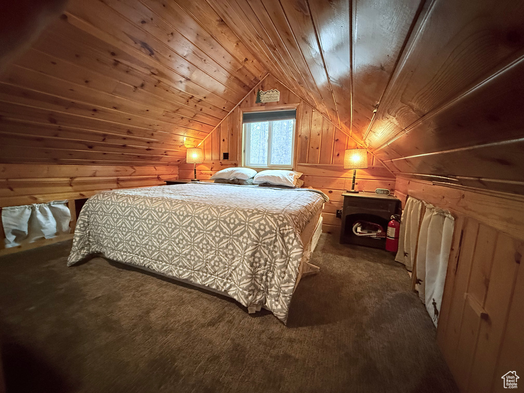 Bedroom with wood walls, dark colored carpet, lofted ceiling, and wood ceiling