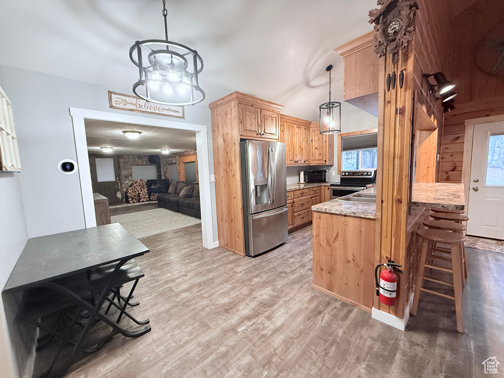 Kitchen featuring stainless steel appliances, light wood-style floors, healthy amount of natural light, and a peninsula