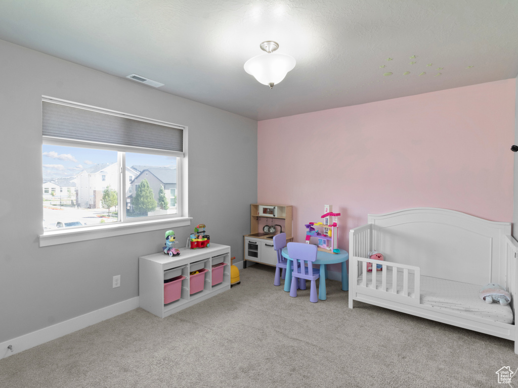 Carpeted bedroom with a crib and baseboards
