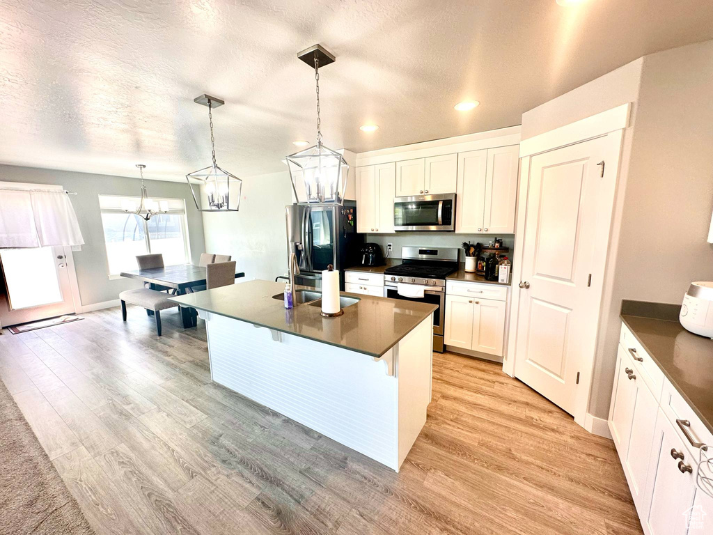 Kitchen with stainless steel appliances, dark countertops, recessed lighting, a chandelier, and white cabinets