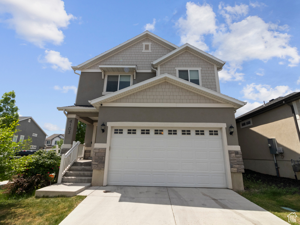 Craftsman-style home featuring stone siding, driveway, stucco siding, and a garage