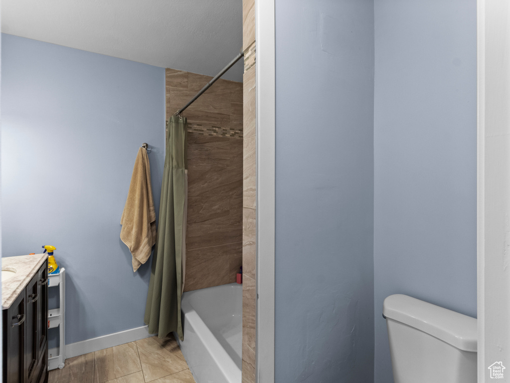 Bathroom with vanity, toilet, shower / bathtub combination with curtain, and baseboards