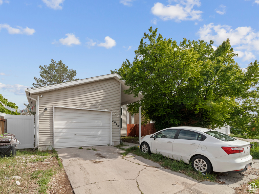 View of side of home featuring fence and concrete driveway