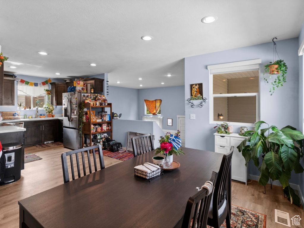 Dining room with light wood finished floors and recessed lighting